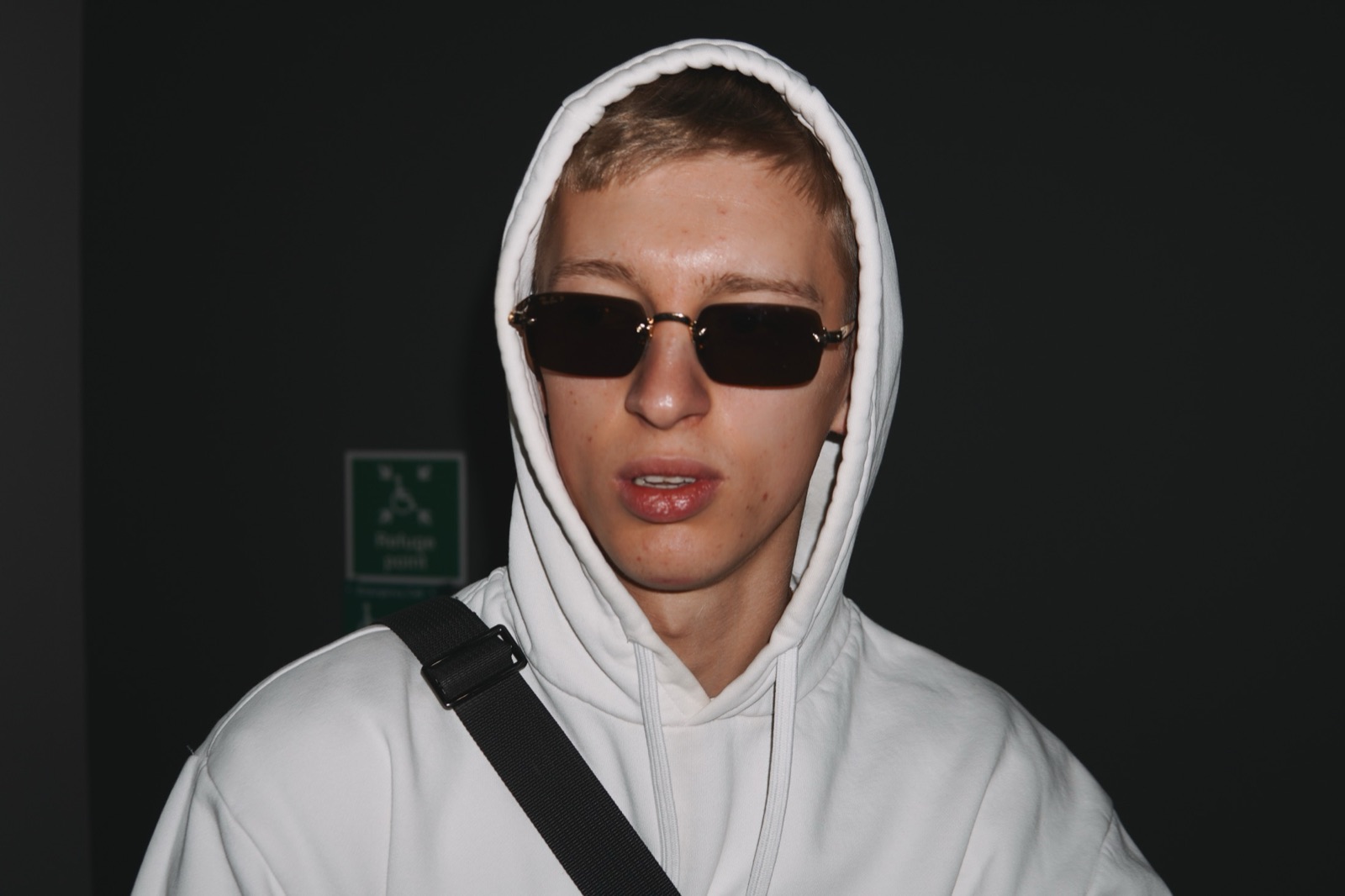 Cinematic portrait of a young man in a white hood and dark sunglasses