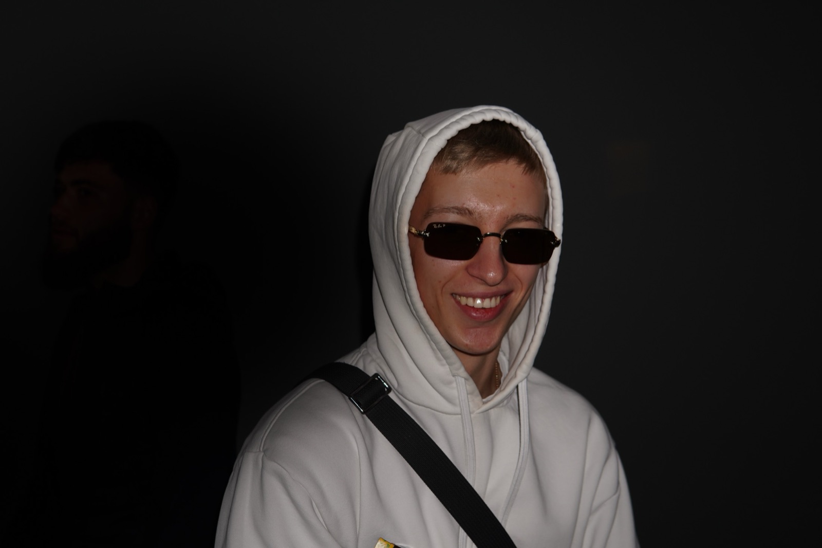 Portrait of a smiling young man in a white hood and sunglasses