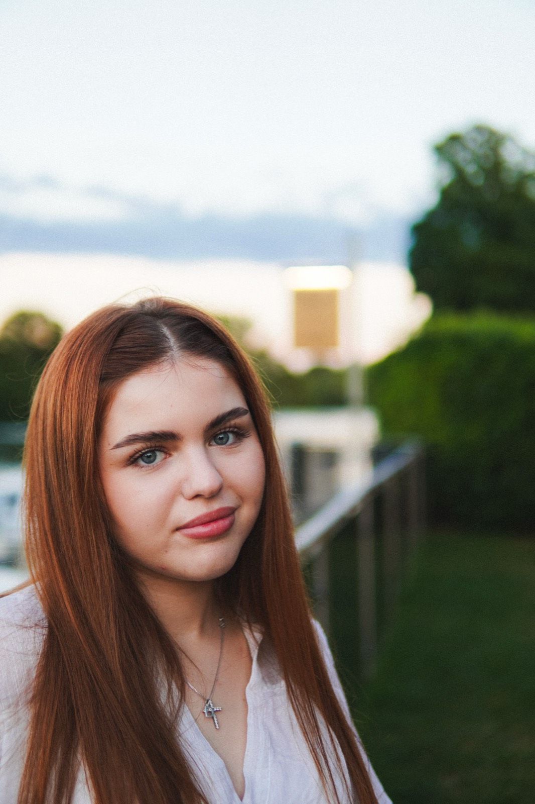 Portrait of a red-haired woman in a white shirt at dusk